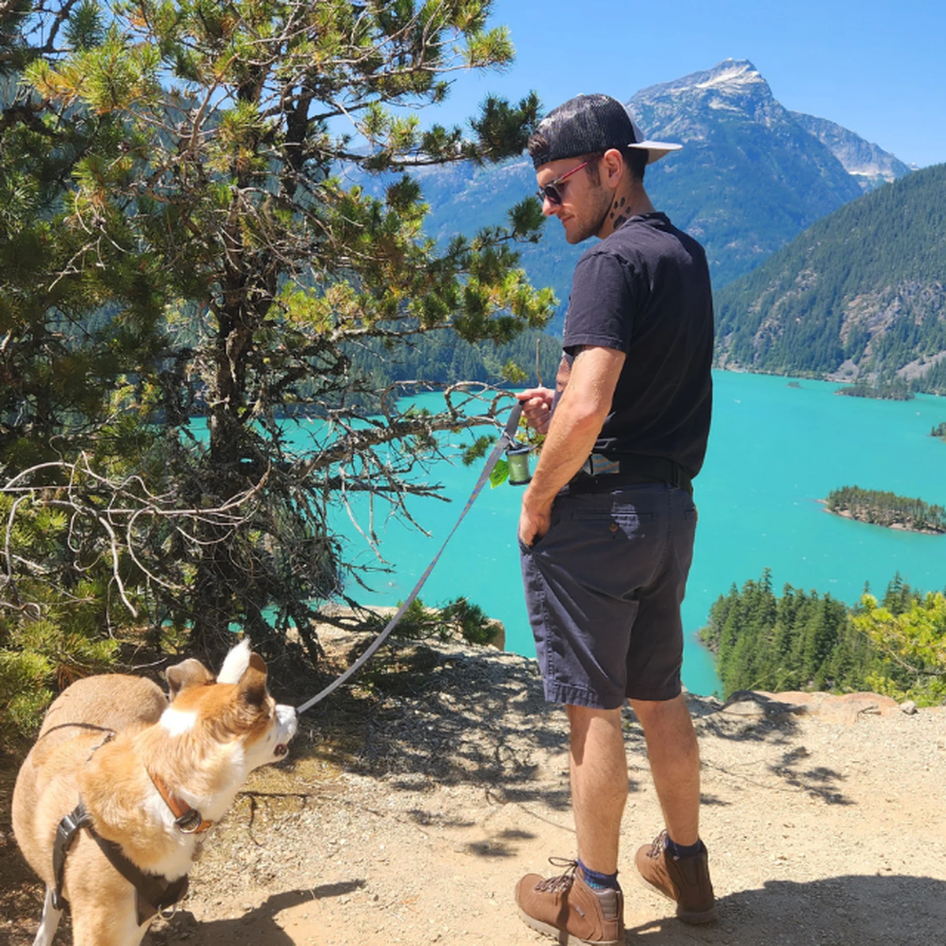 Alex stands at a scenic viewpoint of Diablo Lake in North Cascades National Park, looking at and listening to his dog Joey